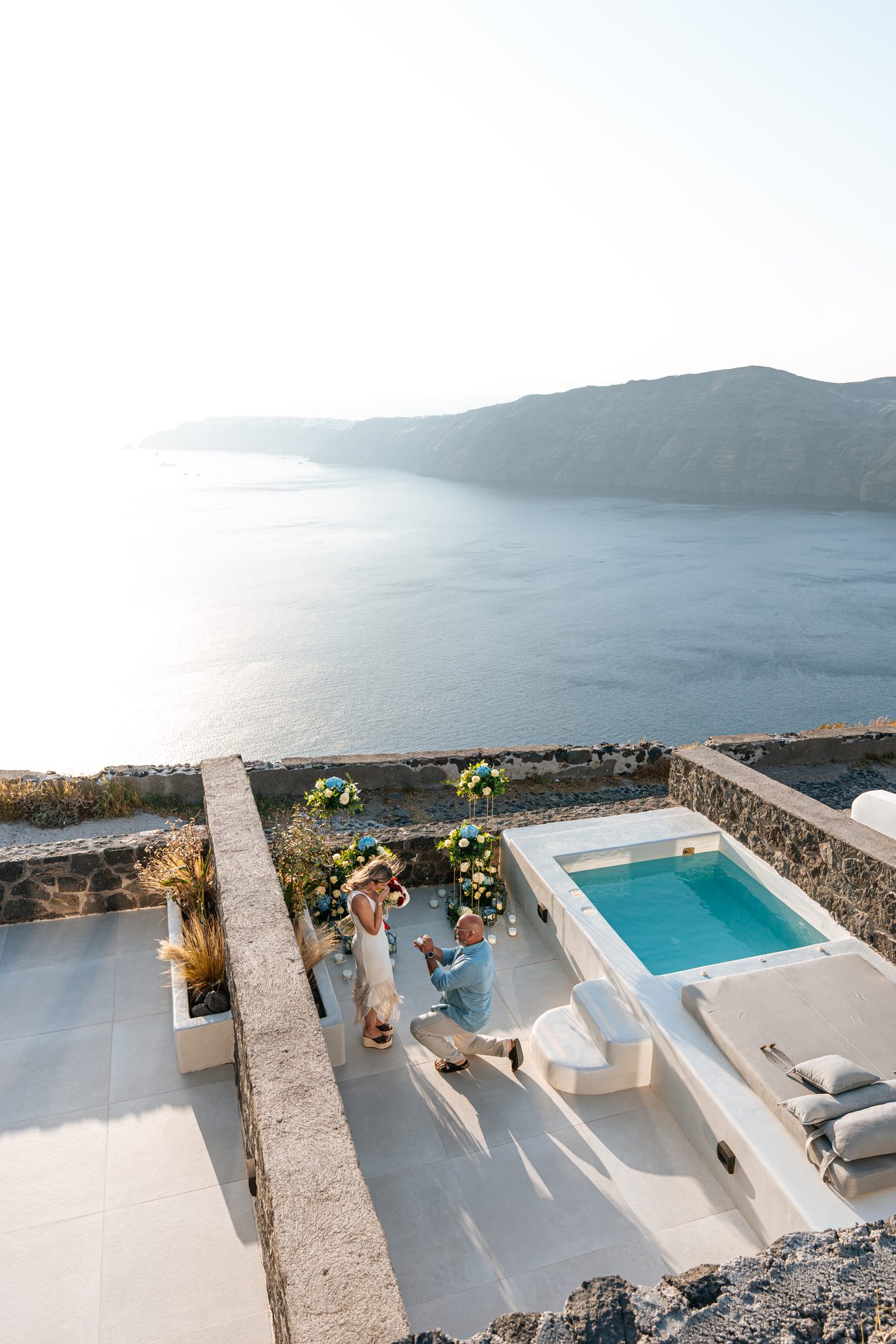 Man on one knee proposing on a villa terrace above the Santorini caldera, Imerovigli