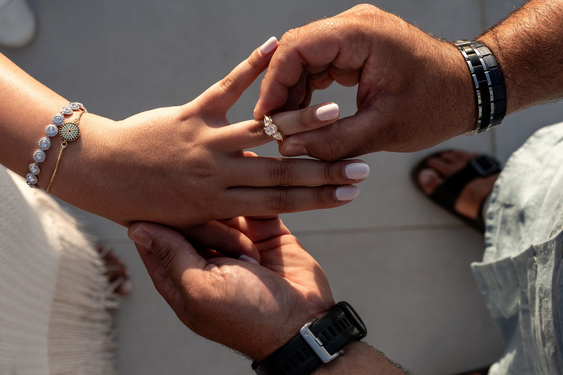 Placing the engagement ring on her finger after a surprise proposal in Imerovigli, Santorini