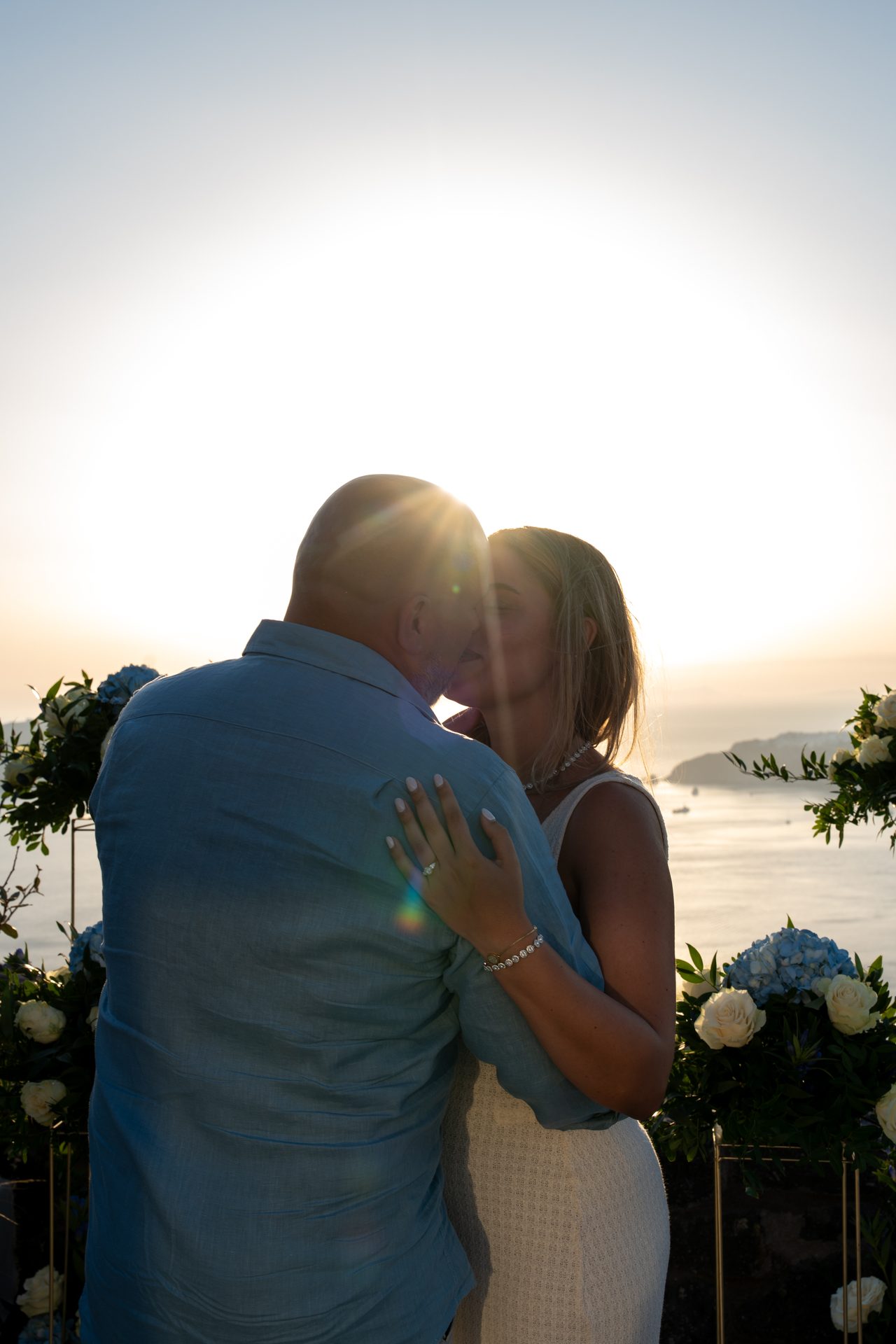 Silhouette of a newly engaged couple embracing against the Santorini sunset
