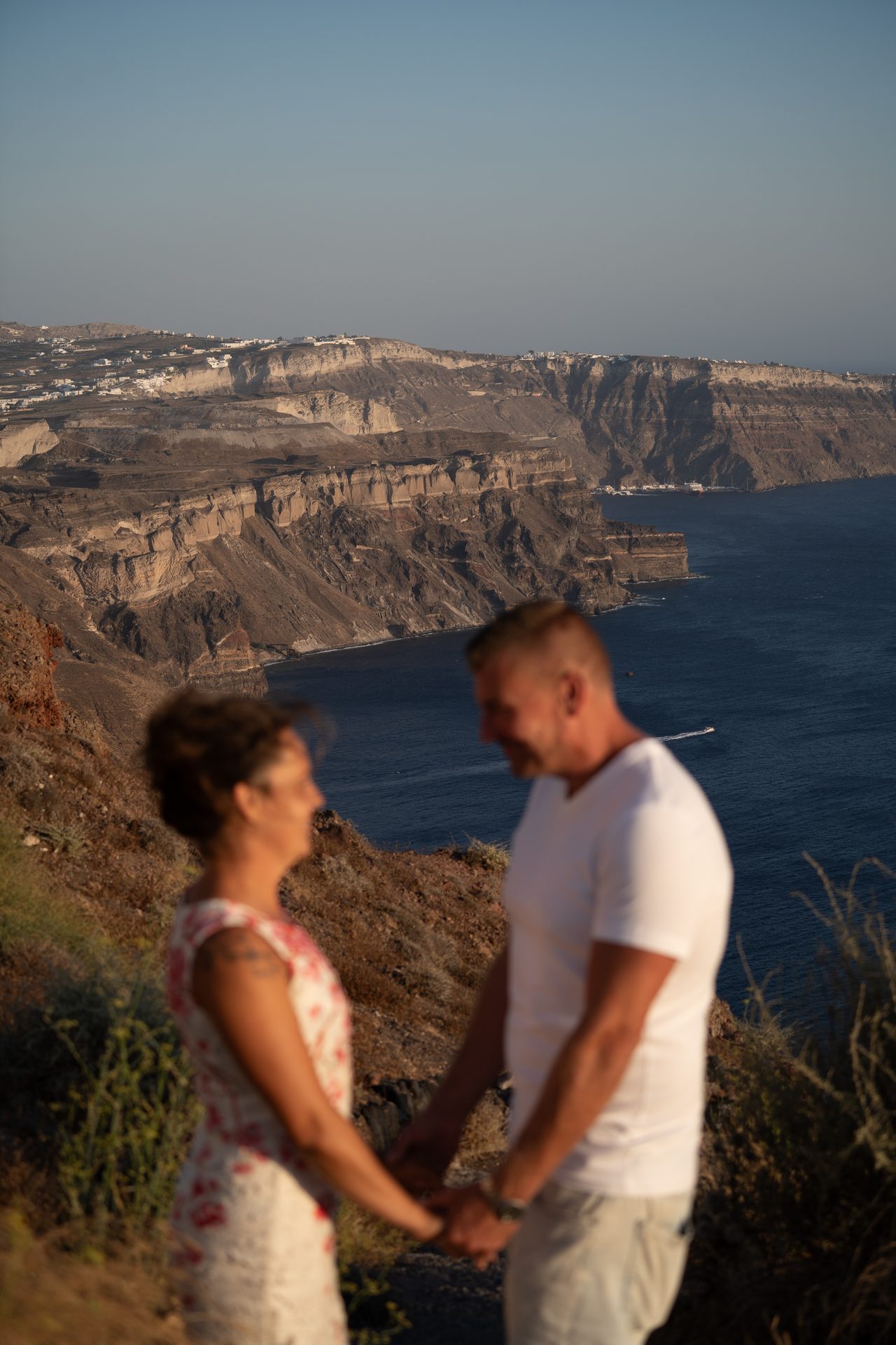 Couple at the Skaros Rock chapel terrace at golden hour, Santorini