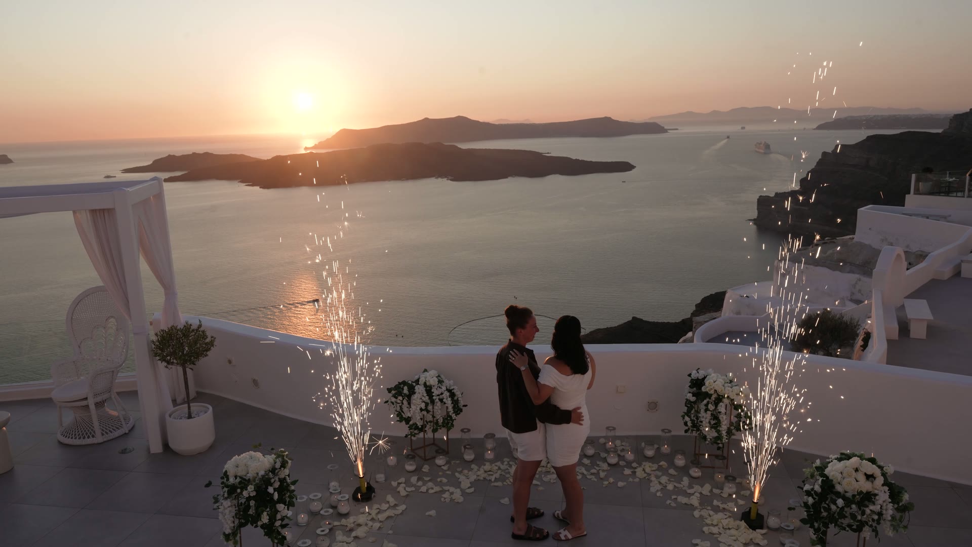 Couple embracing on a sparkler-lit terrace above the Santorini caldera, a still from a proposal film by Alexandros Sirigos