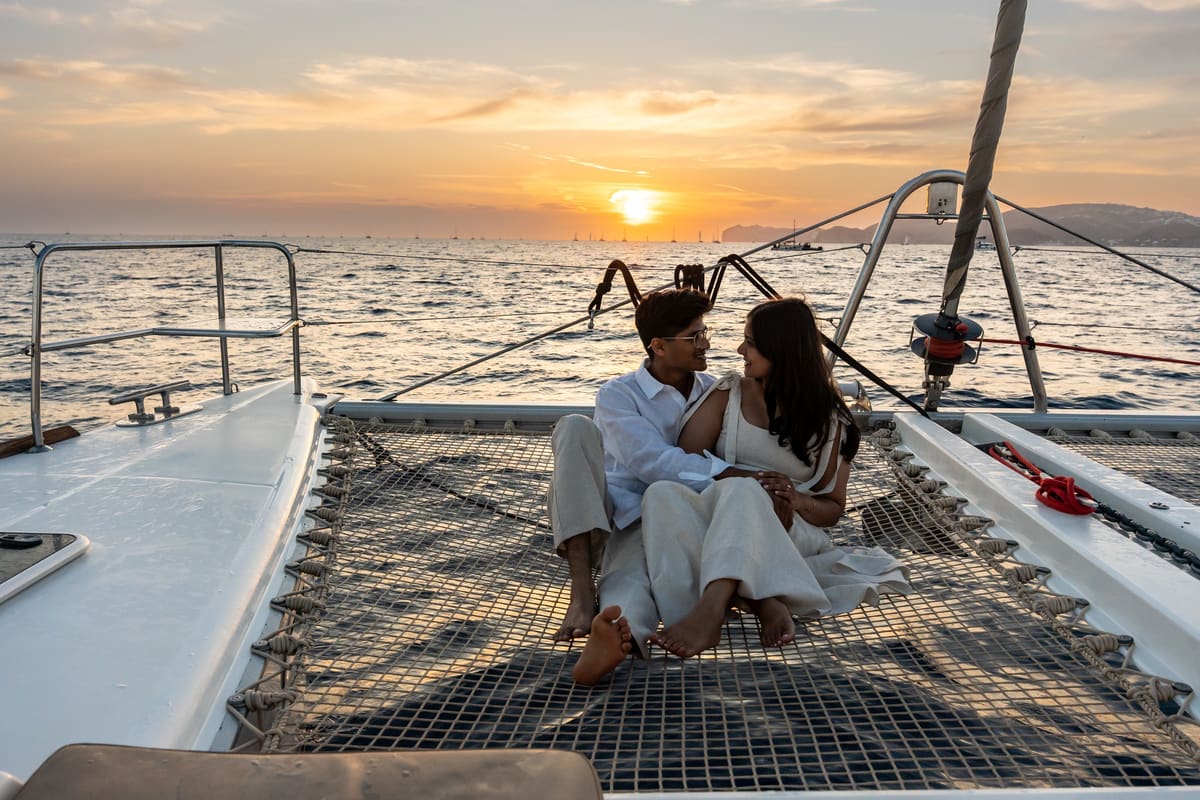 Couple seated on a catamaran bow at sunset on the Santorini caldera