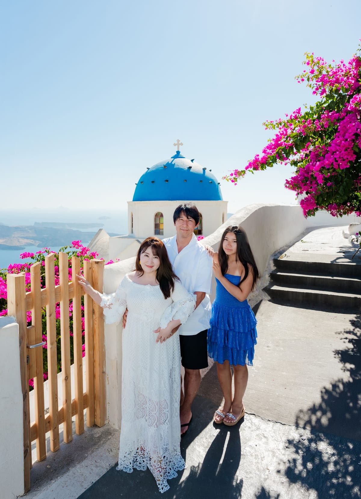 Parents and daughter at the Anastasi church gate with bougainvillea, Imerovigli, Santorini
