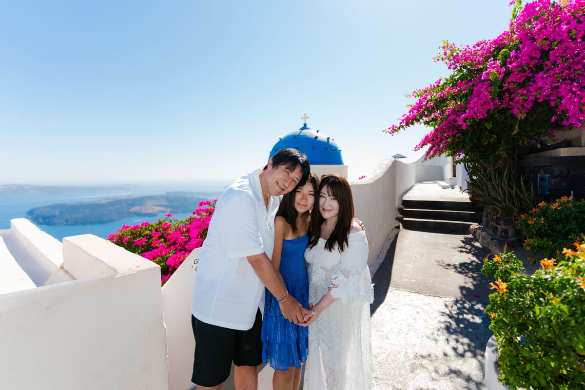 Mother and daughter hugging dad at the Imerovigli blue dome, Santorini family photoshoot