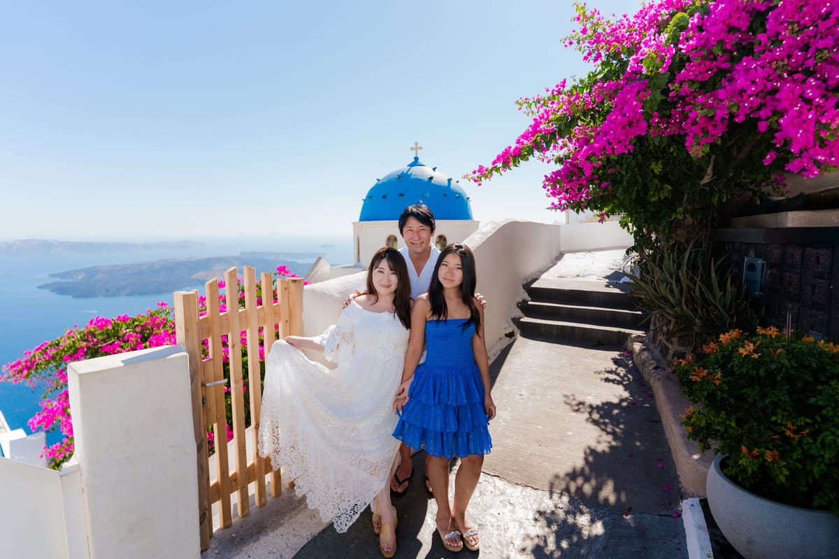 Family of three at the wooden gate of the blue dome in Oia, Santorini