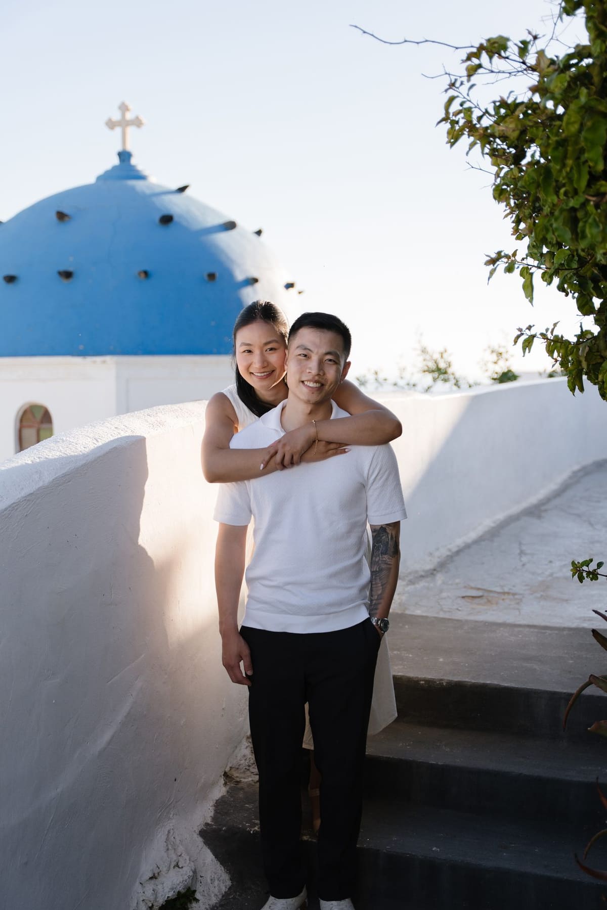 Couple in white embracing next to the blue dome of Oia, Santorini photo tour