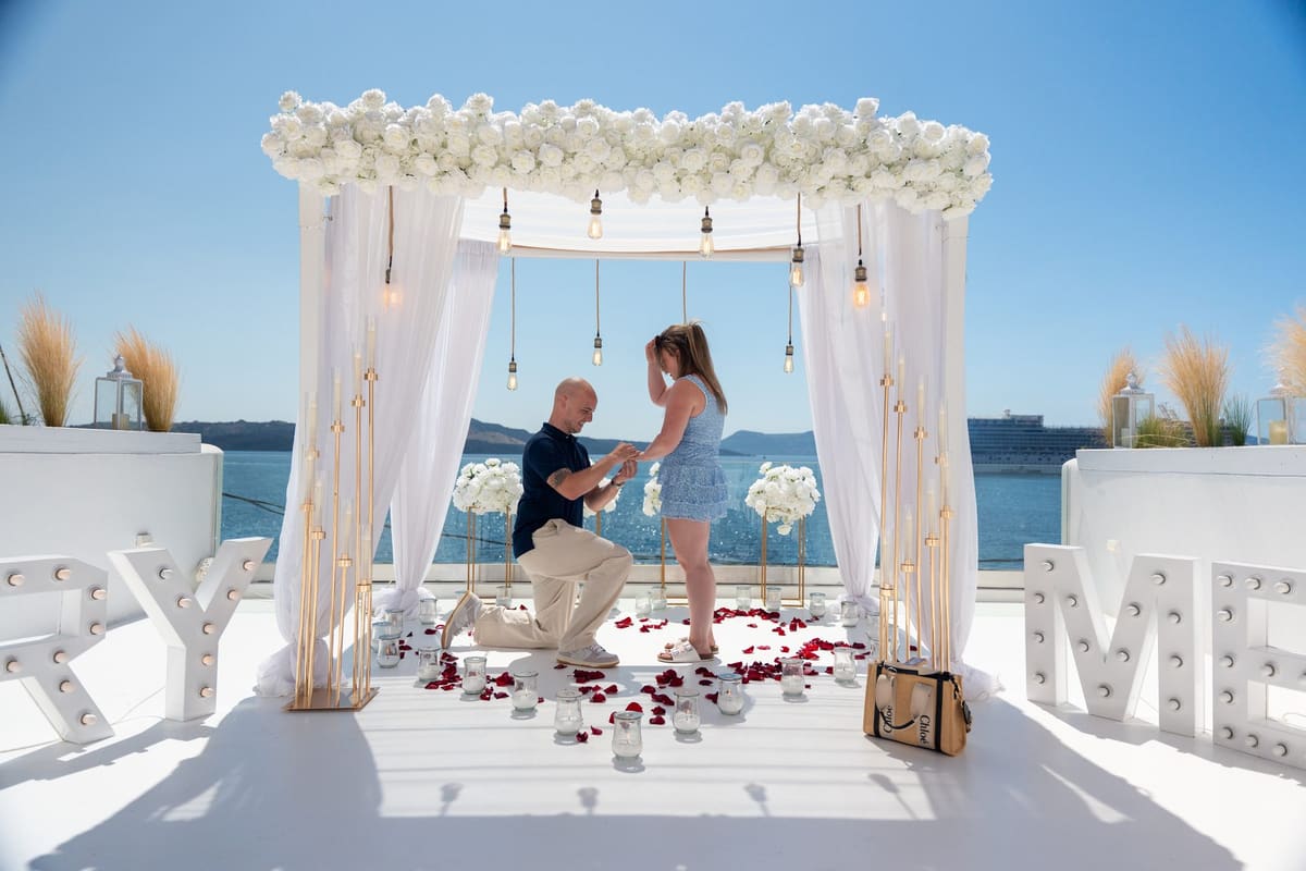 Wide view of the proposal under the canopy with MARRY ME letters and the caldera, Santorini