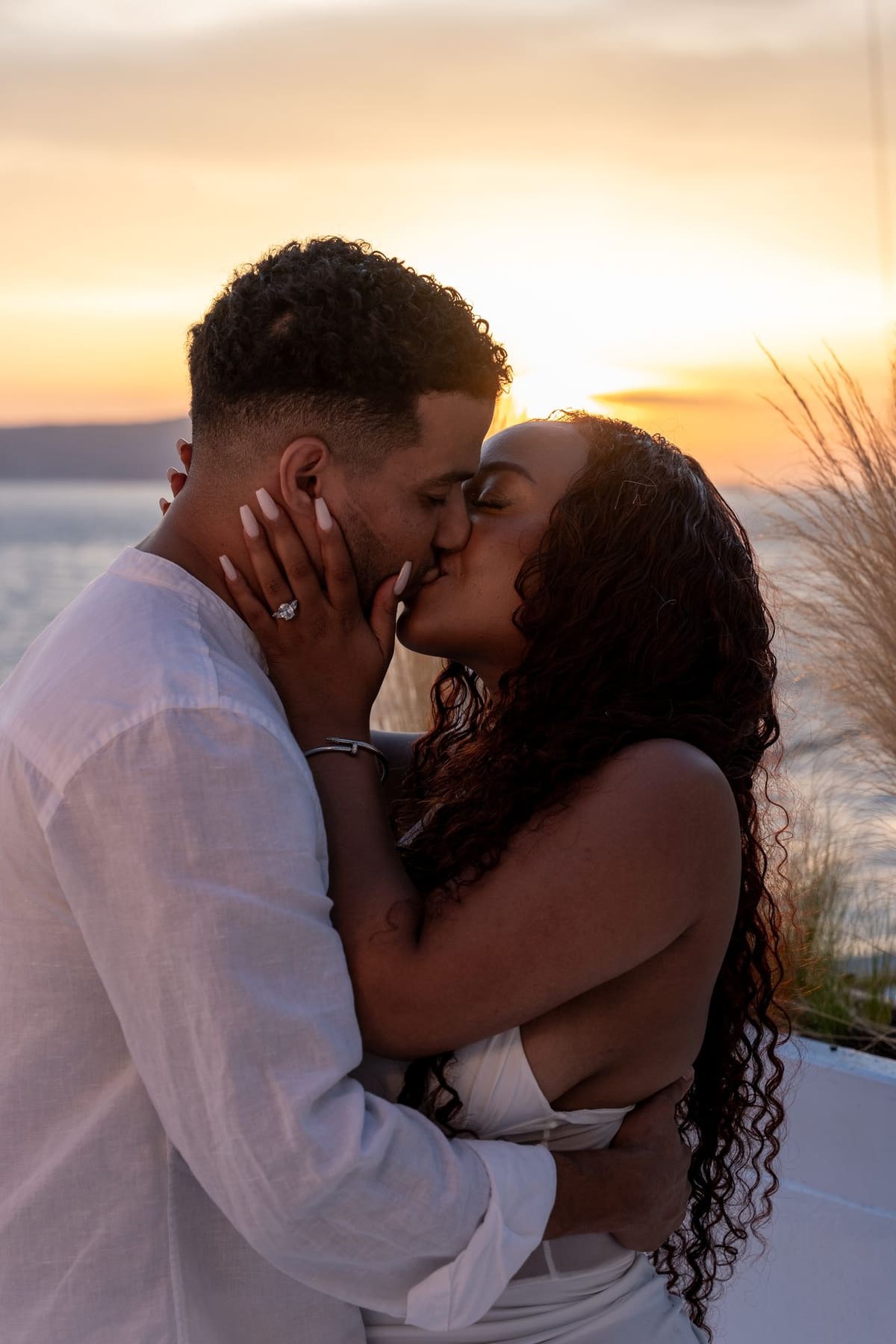 Close kiss in warm sunset light at the old port of Fira, Santorini proposal