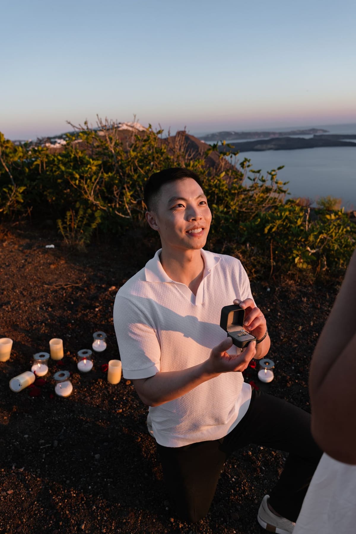 Man smiling and holding the ring box after she said yes, Santorini cliff proposal