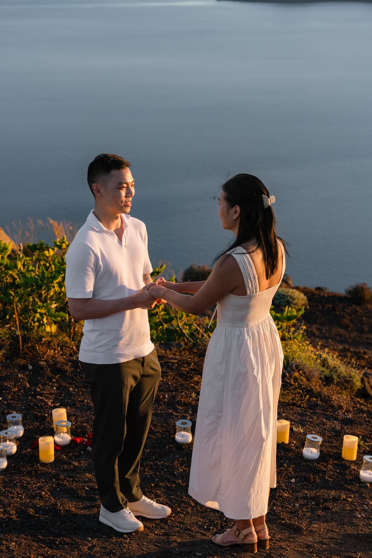 The moment of the proposal on a candle-lined cliff path in Imerovigli at sunset
