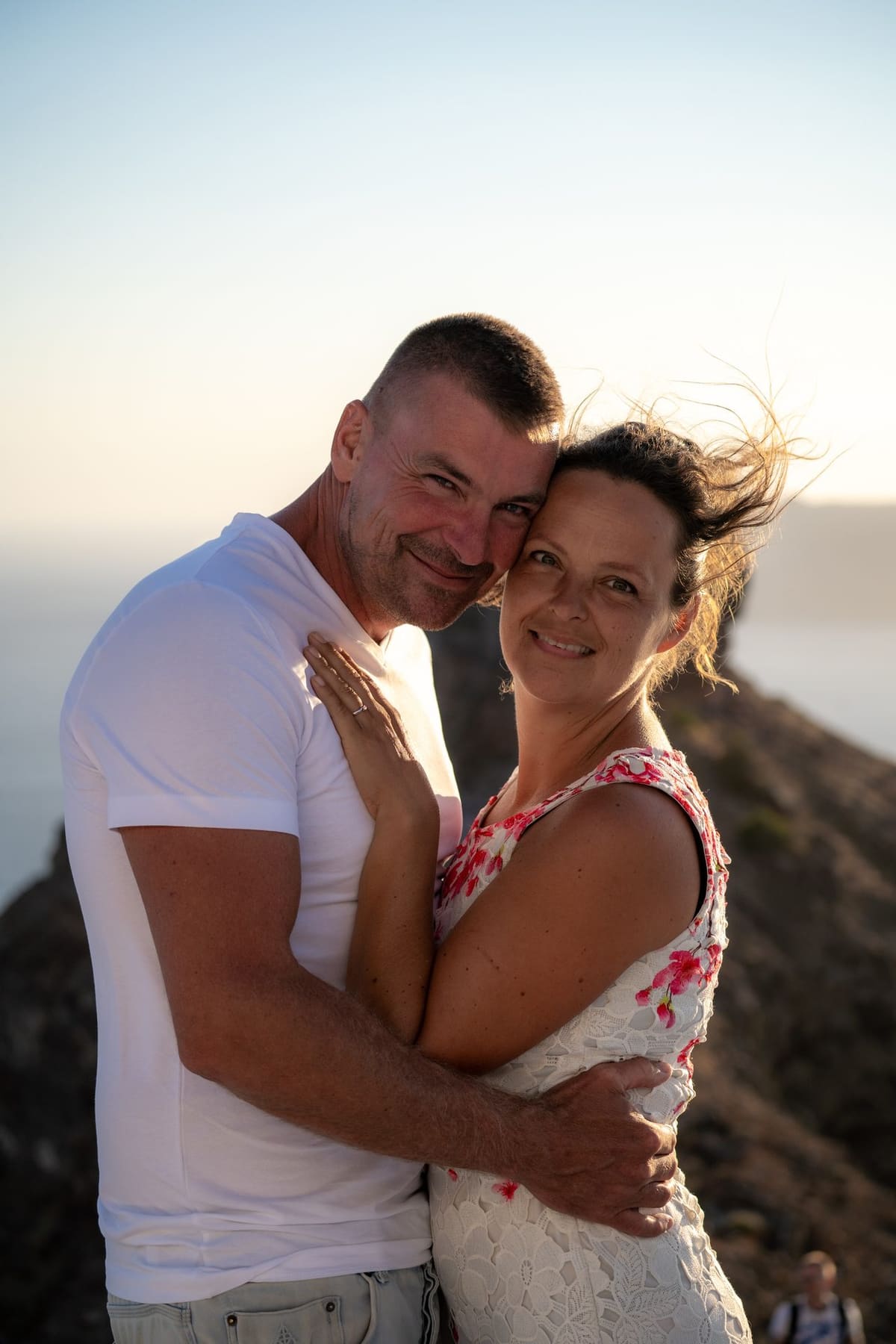 Couple embracing on the cliff at sunset, Skaros Rock session, Imerovigli