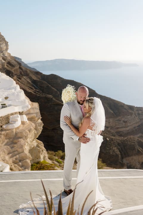 Bride and groom embracing on a whitewashed terrace above the Santorini caldera