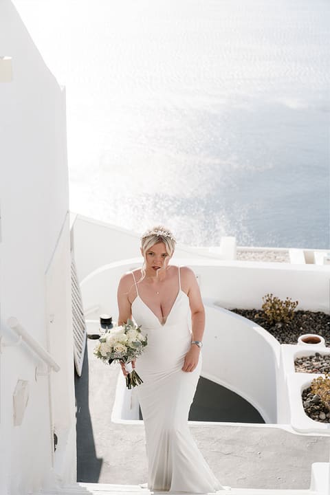 Bride walking down the white steps of a Santorini villa before the ceremony, Imerovigli