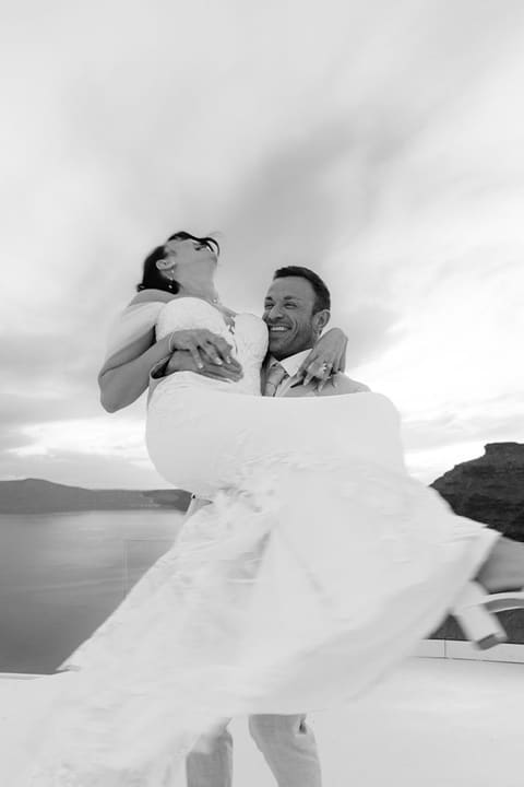 Groom lifting the bride on a caldera terrace in Imerovigli, black and white wedding photo